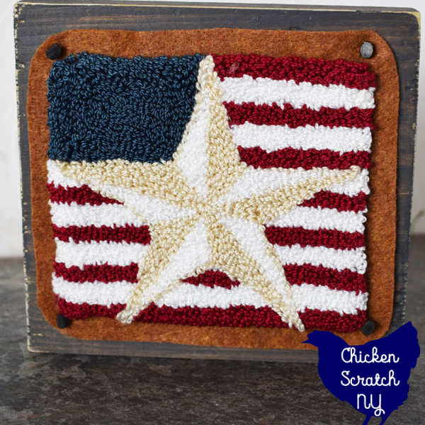 punch needle barn star mounted on felt and attached to a wooden block